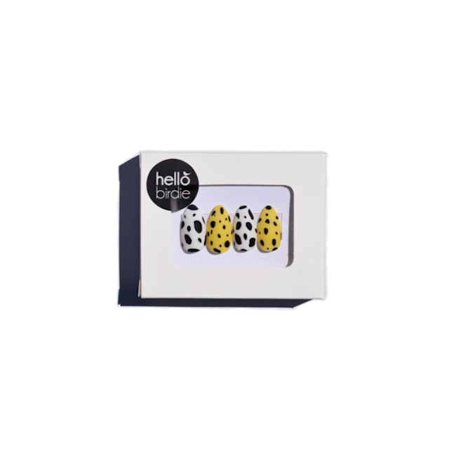 A white box with Hello Birdie brand press on nails painted with bold yellow, white, and black prints