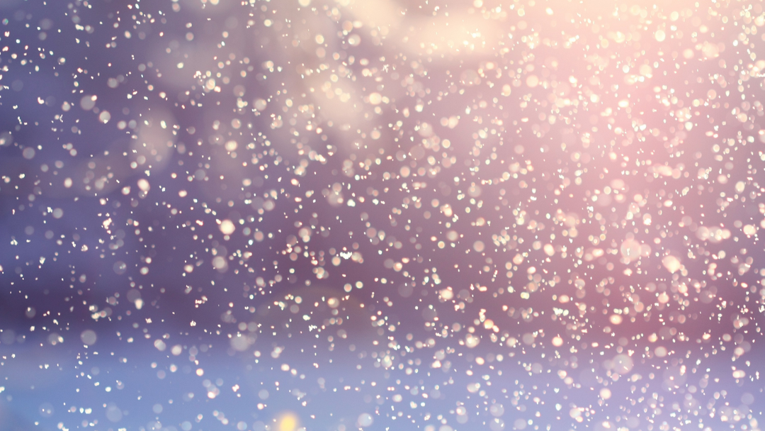 A blurry purple and pastel yellow image of sunlight shining through snowflakes