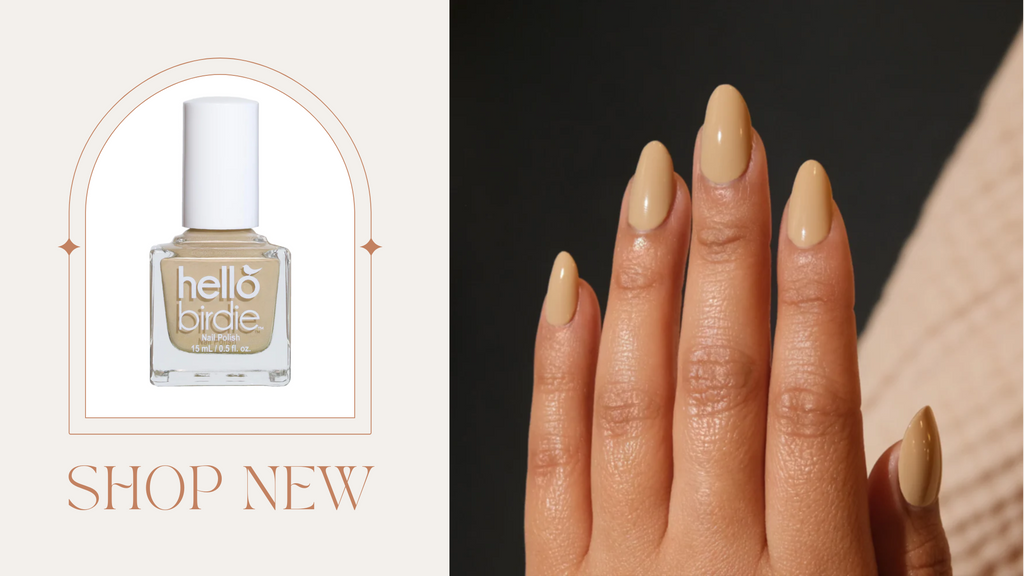 A manicured hand with medium oval nails, next to it a framed bottle of a latte tan Hello Birdie nail polish