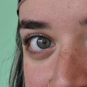 Close-up of a person wearing a leopard print headband against a green background after a lash lift service