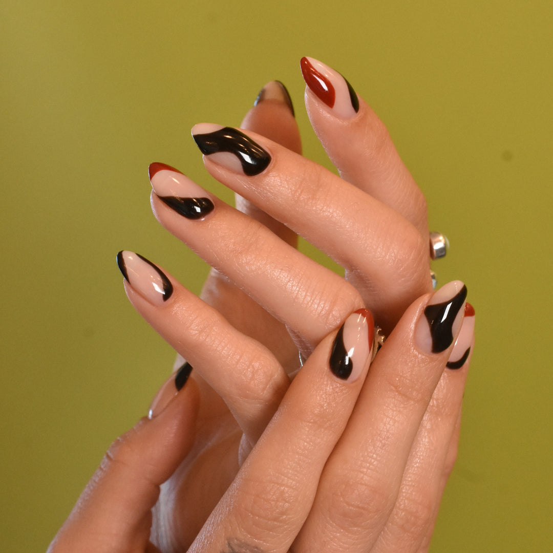 Close-up of a hand with structure gel sculpted nails and black and red nail  art with gel polish on a yellow background
