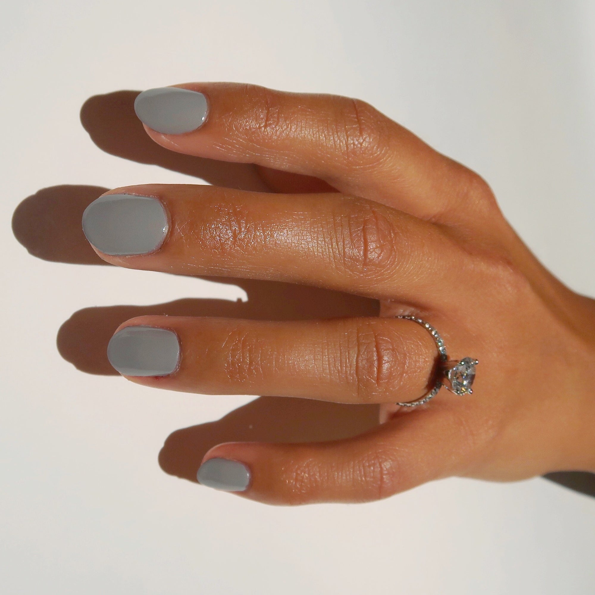 For Flocks Sake is a muted taupe hue, pictured here the single polished hand of a model with squoval shaped nails.  An elegant diamond ring is on her ring finger.  The image is clean and crisp with a white background to support this clean beauty nail polish.