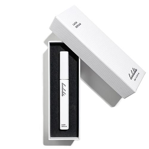 Borboleta Lash Serum white matte plastic dispenser inside of white textured box cushioned in black foam